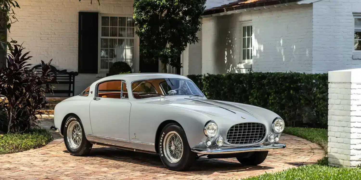 Ferrari 250 Europa GT Coupé von 1955 in silber-grau mit Pinin-Farina-Karosserie, geparkt vor einer weißen Villa.