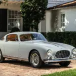Ferrari 250 Europa GT Coupé von 1955 in silber-grau mit Pinin-Farina-Karosserie, geparkt vor einer weißen Villa.