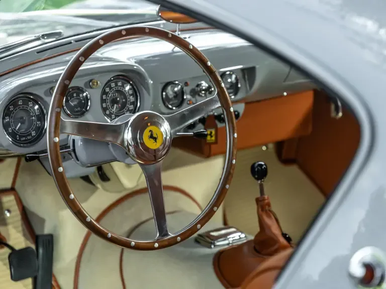 Cockpit des Ferrari 250 Europa GT von 1955 mit Holzlenkrad, klassischen Anzeigen und braunem Leder.