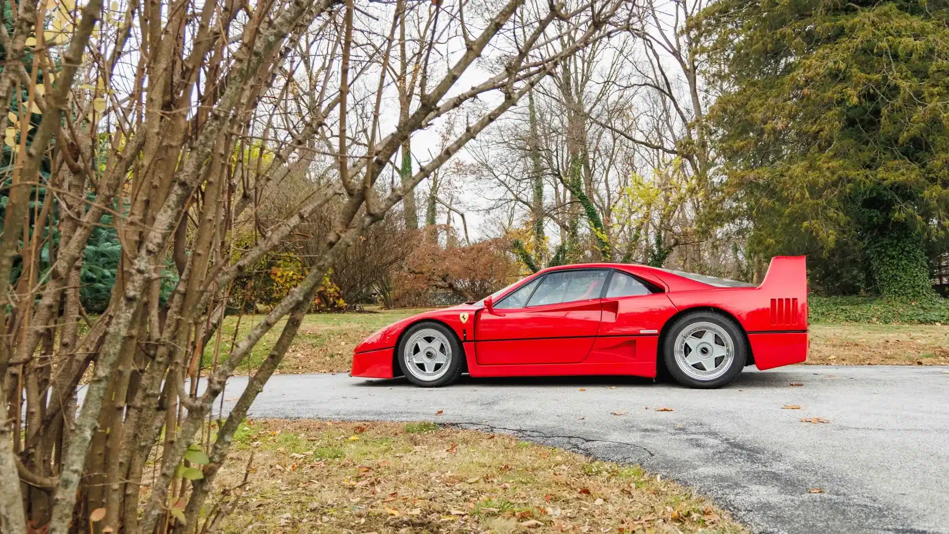 Seitenansicht eines Ferrari F40 in Rosso Corsa von 1991, geparkt im Freien.