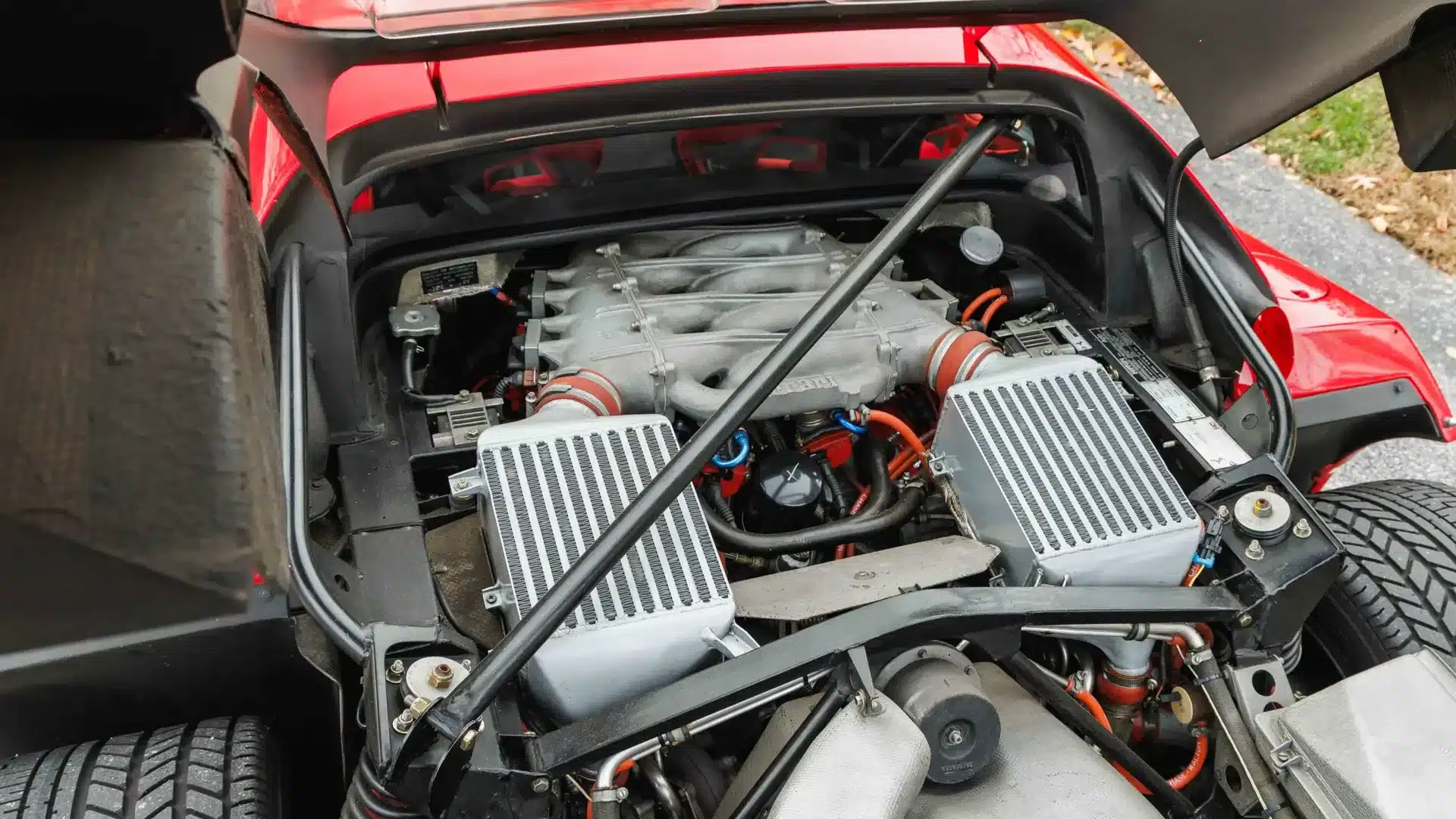Detailaufnahme des Motorraums eines Ferrari F40 von 1991, V8-Biturbo-Motor mit roten und silbernen Komponenten.