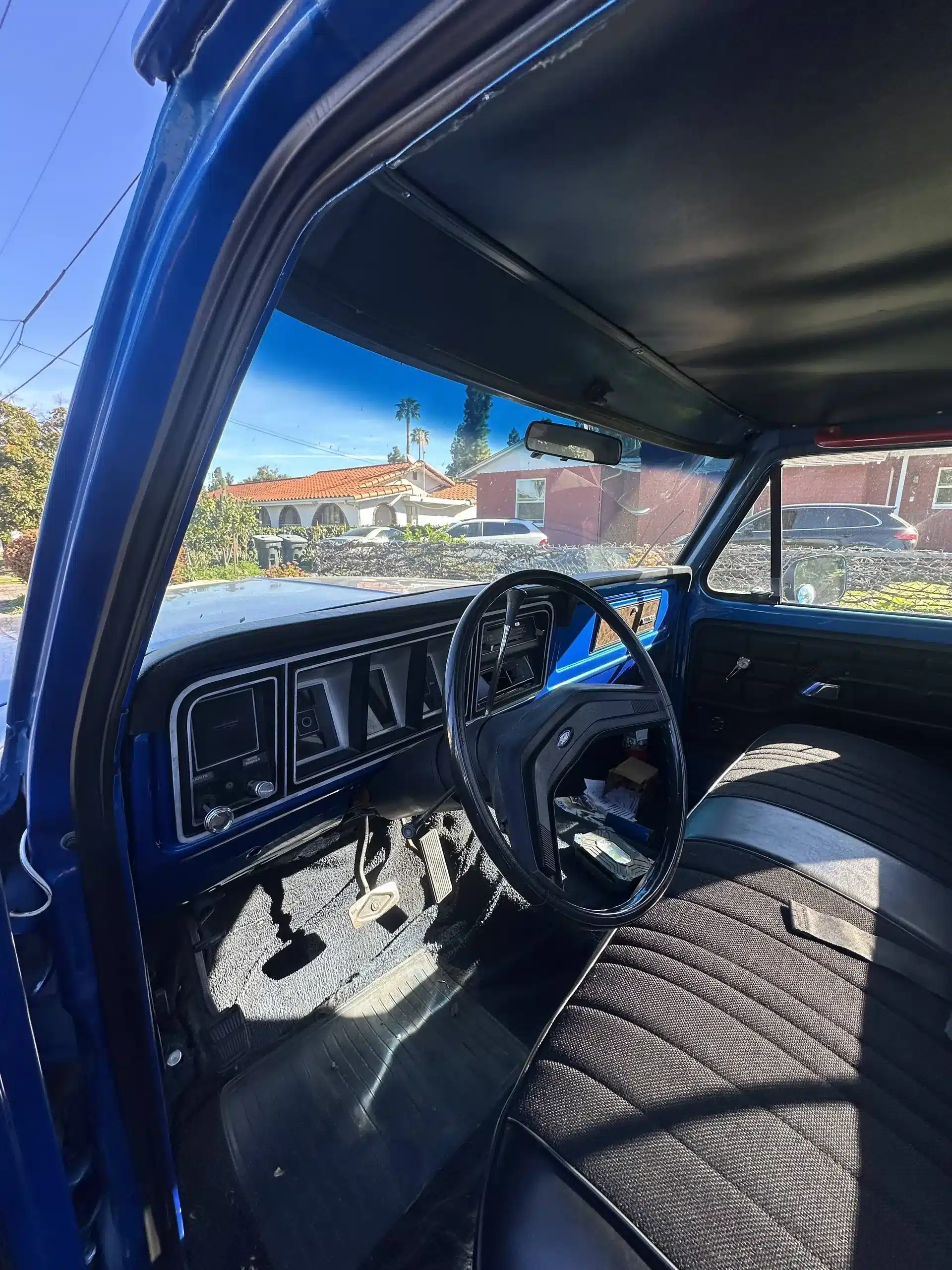Der Innenraum eines blauen Ford F-250 Pick-ups von 1978 mit Lenkrad, Armaturenbrett und Sitzbank.