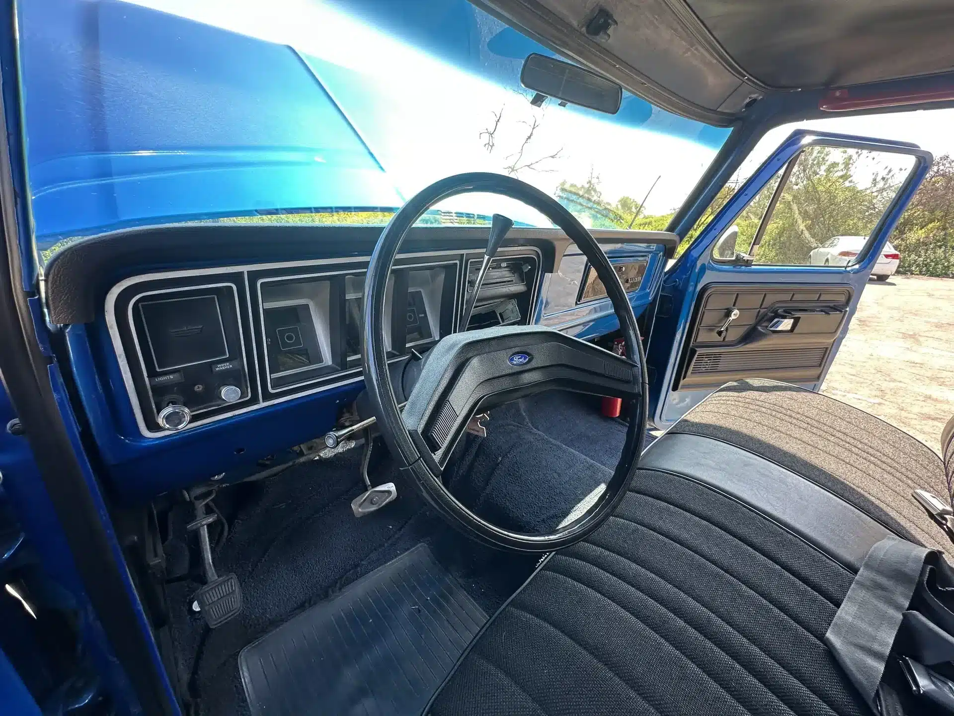 Innenraumansicht eines blauen Ford F-250 Pick-ups von 1978 mit Blick auf Lenkrad, Armaturenbrett und Vordersitzbank