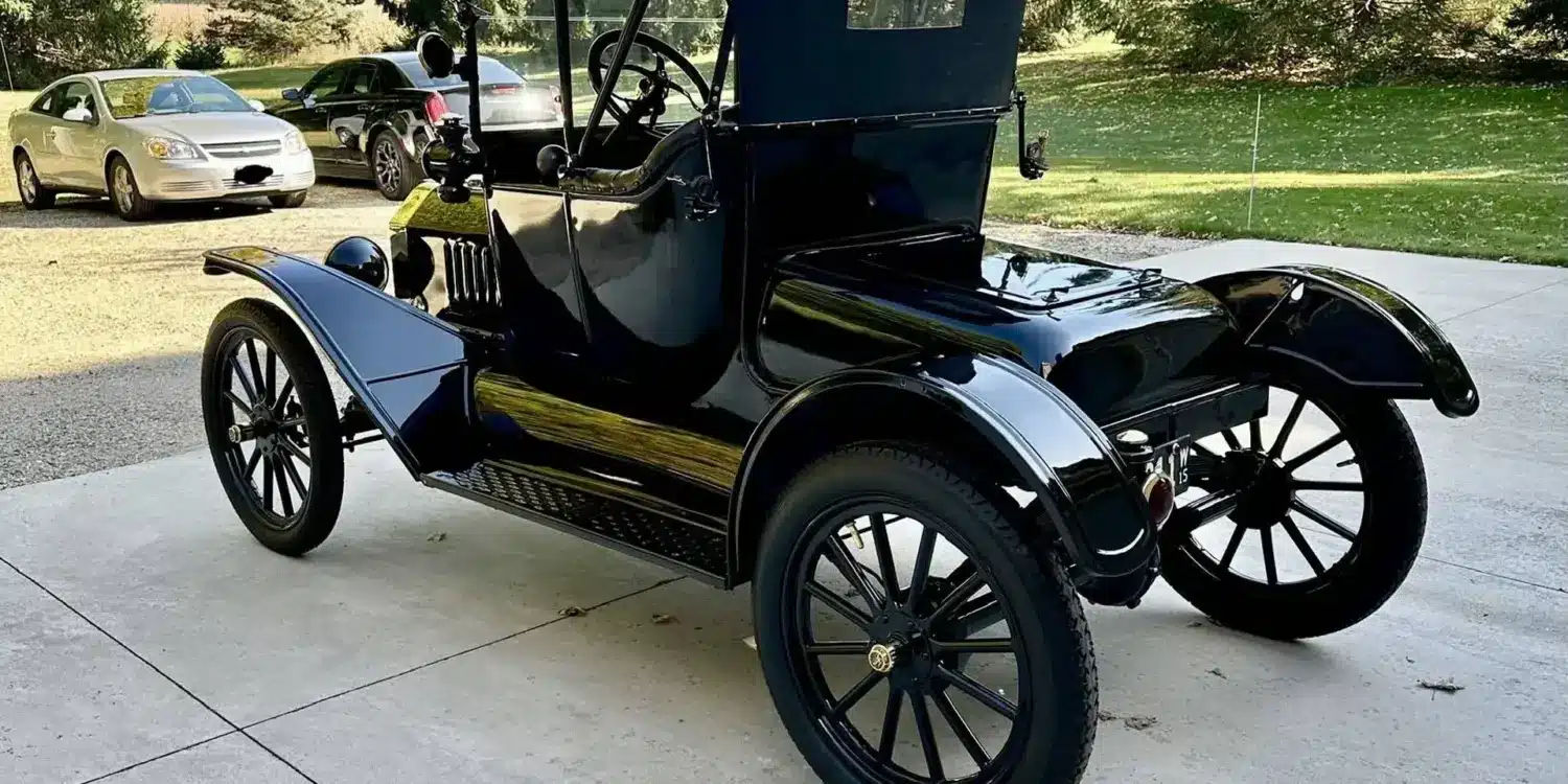 Restaurierter Ford Model T Runabout von 1915, Seiten- und Heckansicht in schwarzer Lackierung, geparkt auf einer Auffahrt mit Bäumen im Hintergrund