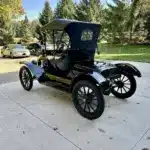 Restaurierter Ford Model T Runabout von 1915, Seiten- und Heckansicht in schwarzer Lackierung, geparkt auf einer Auffahrt mit Bäumen im Hintergrund