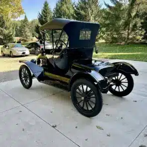 Restaurierter Ford Model T Runabout von 1915, Seiten- und Heckansicht in schwarzer Lackierung, geparkt auf einer Auffahrt mit Bäumen im Hintergrund