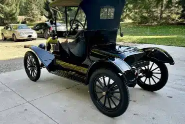 Restaurierter Ford Model T Runabout von 1915, Seiten- und Heckansicht in schwarzer Lackierung, geparkt auf einer Auffahrt mit Bäumen im Hintergrund