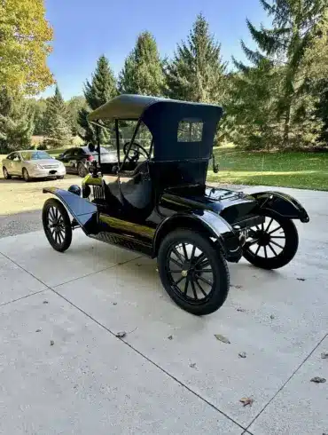 Restaurierter Ford Model T Runabout von 1915, Seiten- und Heckansicht in schwarzer Lackierung, geparkt auf einer Auffahrt mit Bäumen im Hintergrund