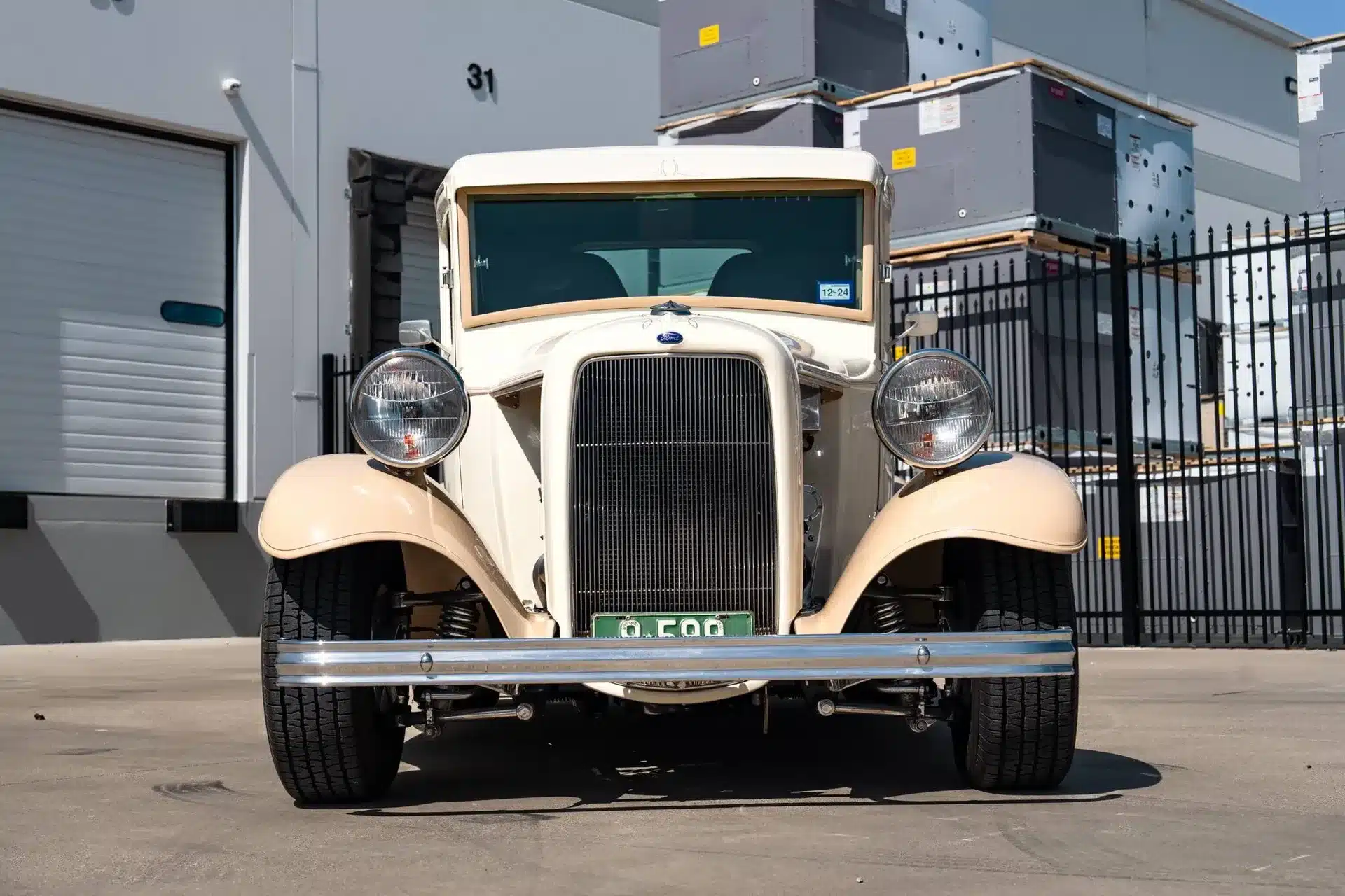 Ford Pickup von 1932, cremefarben, frontal fotografiert, vor moderner Industriekulisse.
