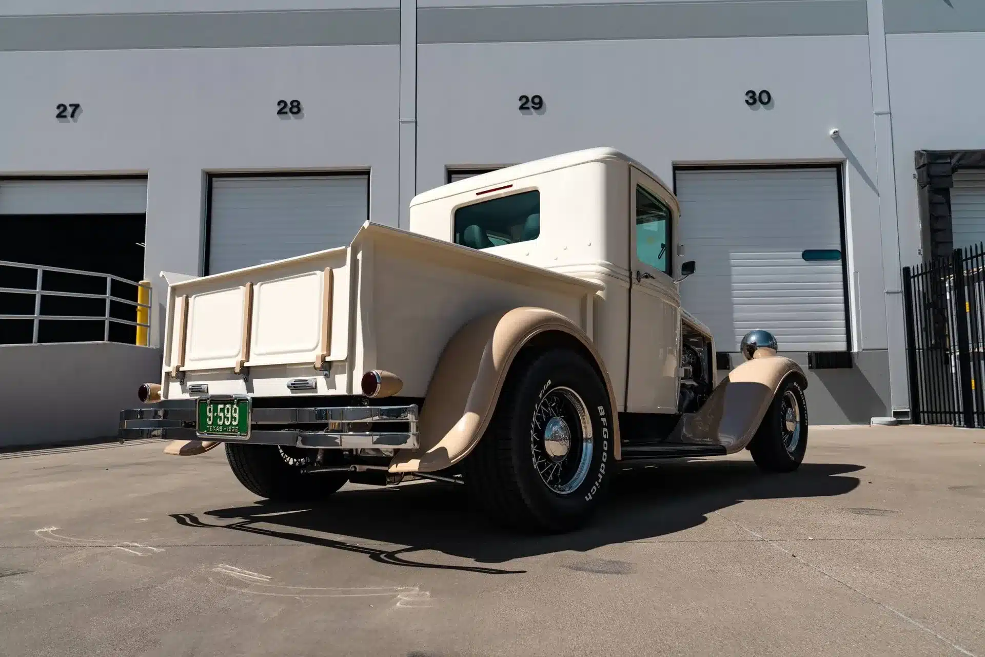 Ford Pickup von 1932 in beigefarbener Lackierung, fotografiert von hinten auf einem Parkplatz vor Industriegebäuden