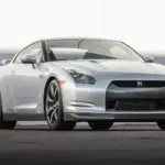 Silberner Nissan GT-R R35 von vorn auf Asphalt vor hellem Hintergrund, Modelljahr 2009.