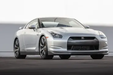 Silberner Nissan GT-R R35 von vorn auf Asphalt vor hellem Hintergrund, Modelljahr 2009.