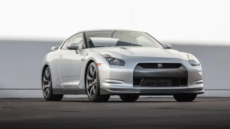 Silberner Nissan GT-R R35 von vorn auf Asphalt vor hellem Hintergrund, Modelljahr 2009.