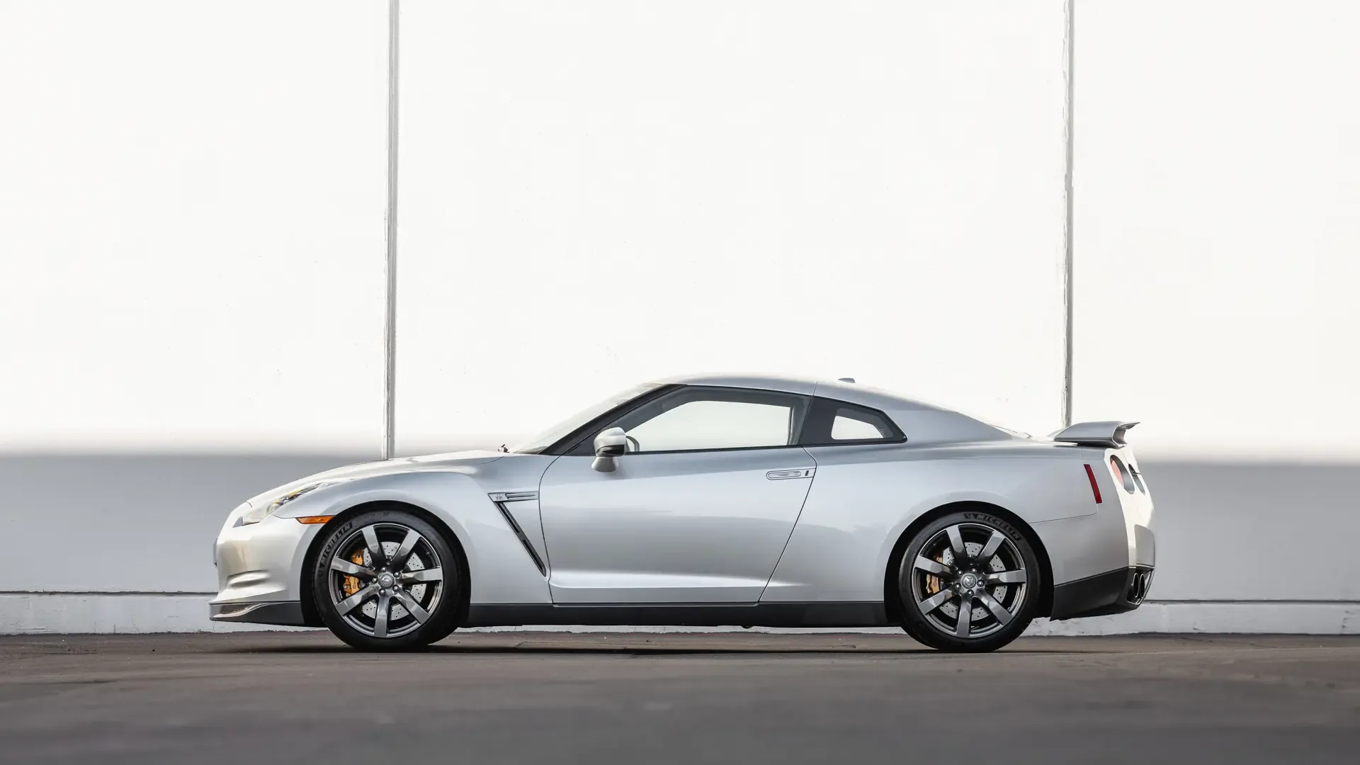 2009 Nissan GT-R R35 in Super Silver, Seitenansicht, sportliches Coupé vor neutralem Hintergrund.