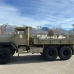 AM General M939 Militär-Lkw Baujahr 1985, beige lackiert, mit drei Achsen und robuster Karosserie vor Bergpanorama