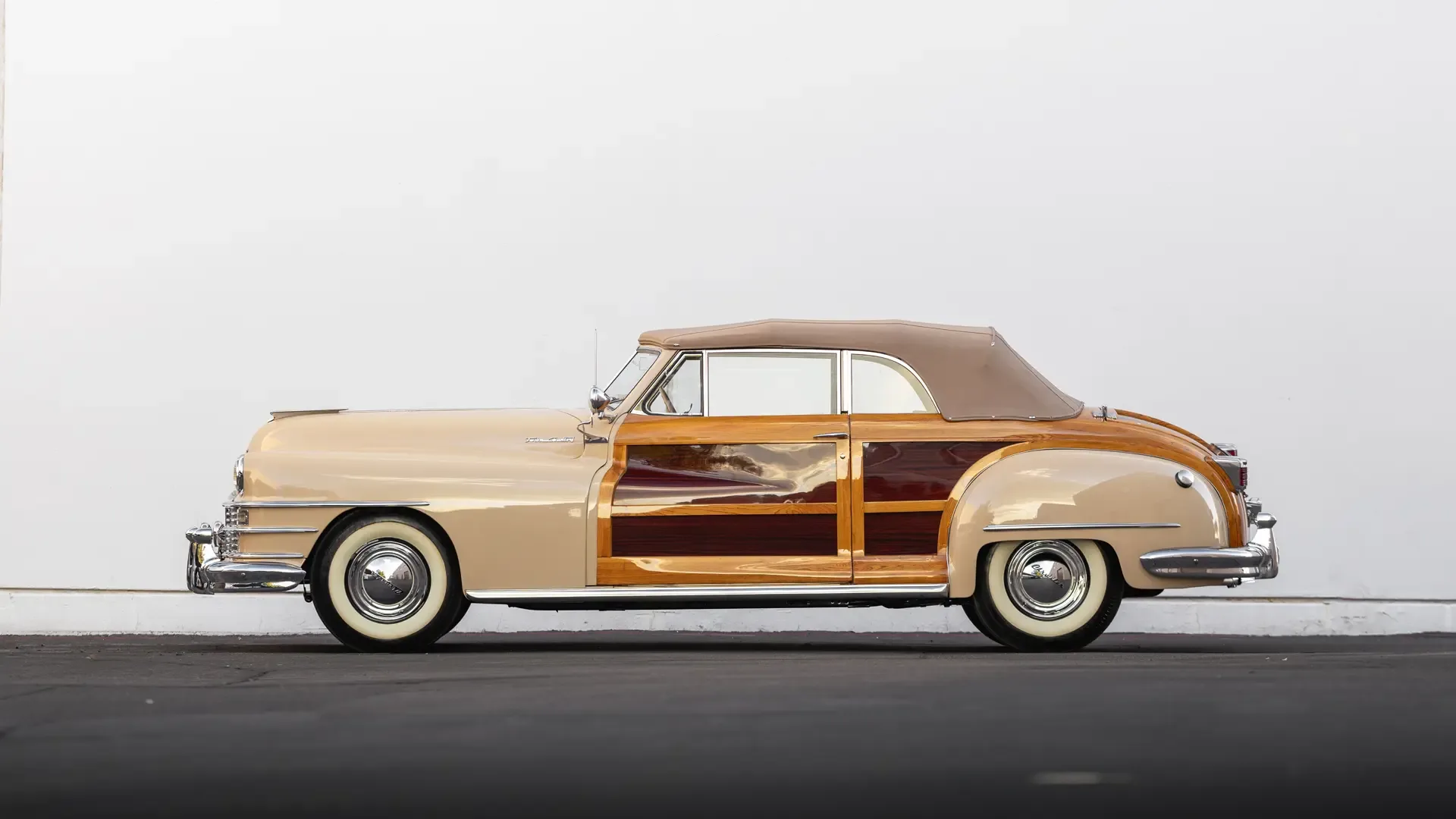 1947er Chrysler Town & Country Convertible in Beige mit Holzbeplankung und Stoffverdeck, seitlich fotografiert