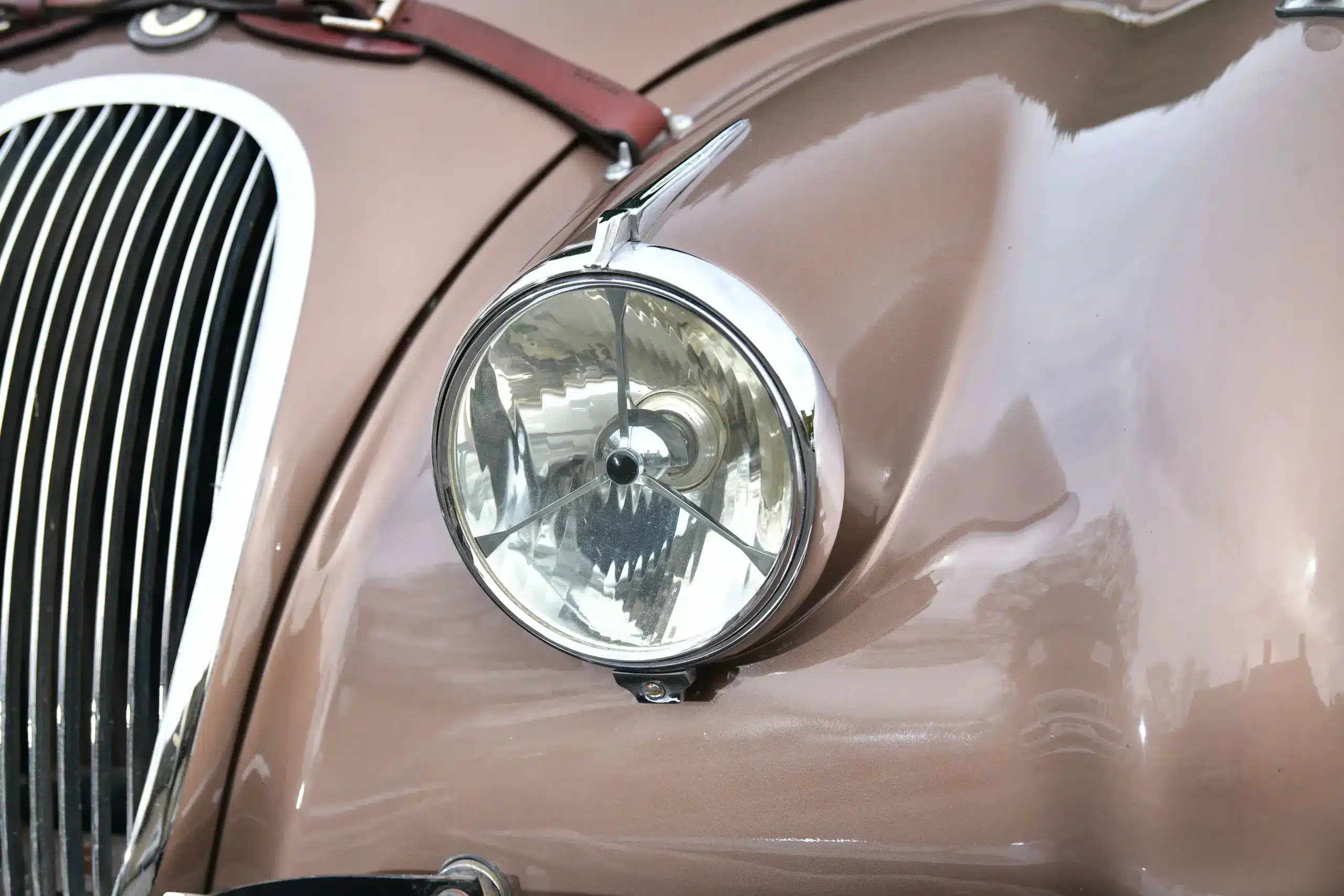 Detailaufnahme eines Scheinwerfers und des Kühlergrills eines klassischen Jaguar XK120 Roadster