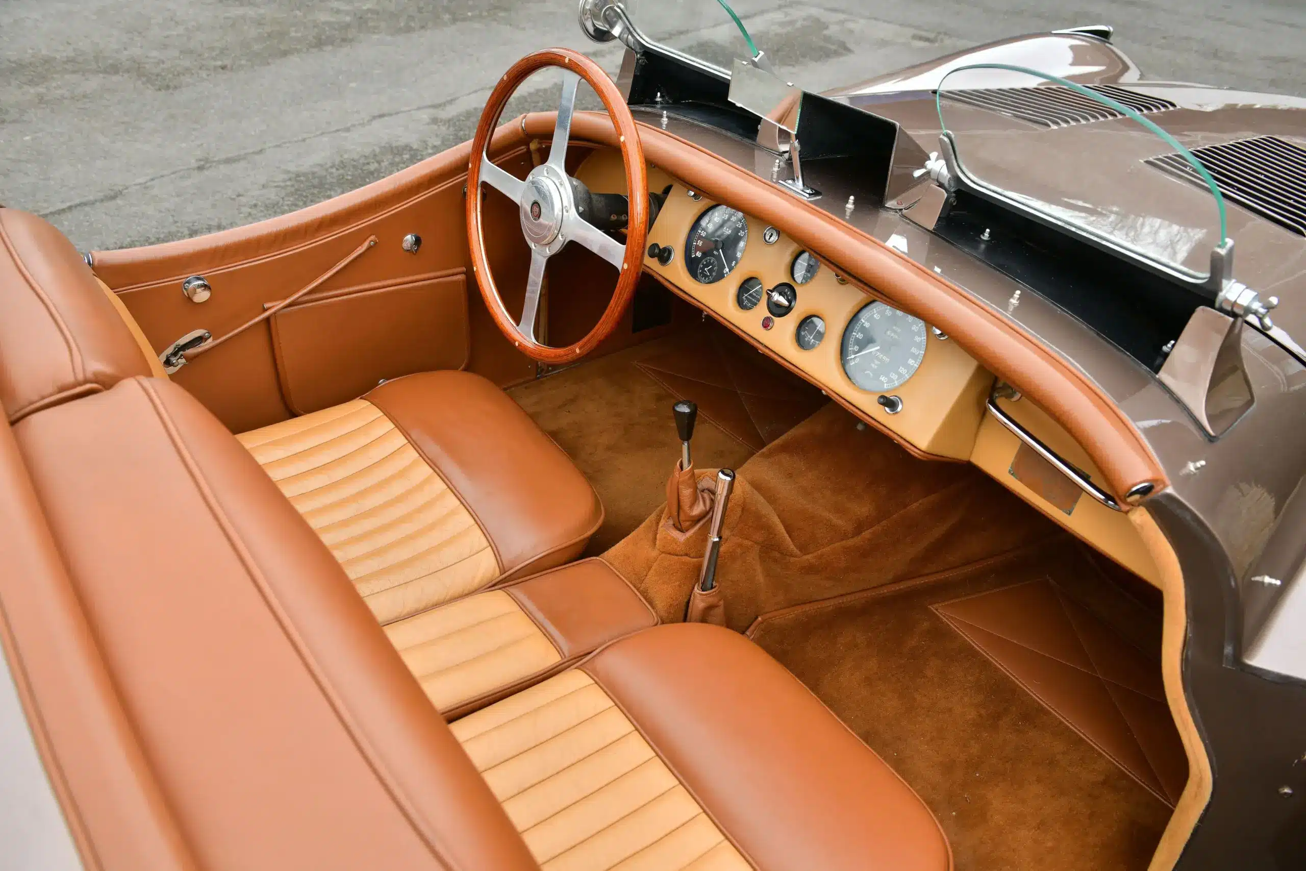 Innenraum eines originalen Jaguar XK120 Roadster von 1950 mit lederbezogenen Sitzen, Holzlenkrad und Armaturenbrett.