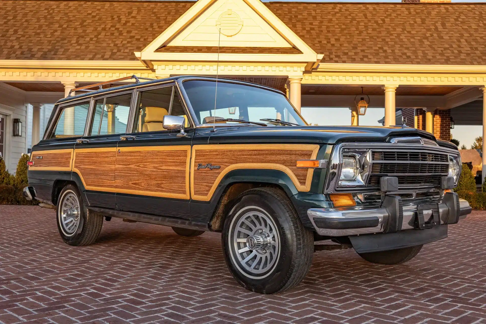Jeep Grand Wagoneer 1991 mit Holzdekor, geparkt auf Ziegelpflaster vor einem klassischen Haus.