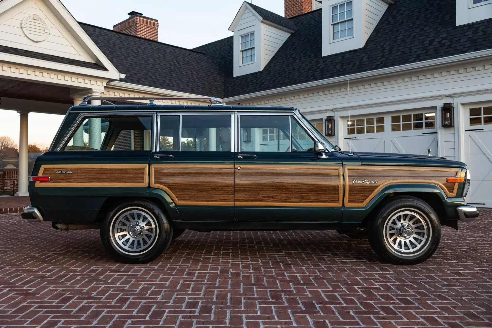 Seitenansicht eines grünen 1991 Jeep Grand Wagoneer mit Holzdekor vor einer repräsentativen Villa