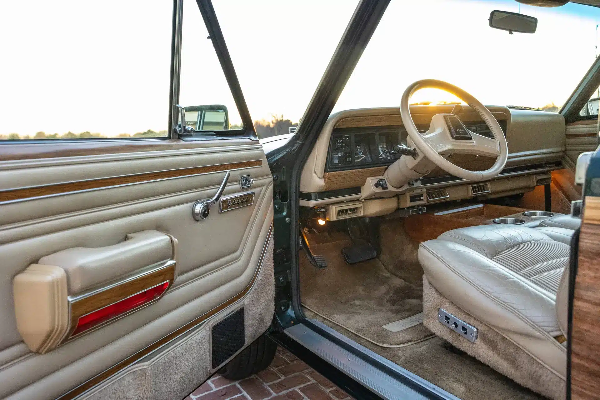Innenraum eines 1991 Jeep Grand Wagoneer mit offenen Fahrertür, Ledersitzen und Armaturenbrett im Vintage-Stil.