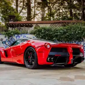 Ferrari LaFerrari 2015 in Rosso Corsa, geparkt in mediterranem Garten, Heckansicht.
