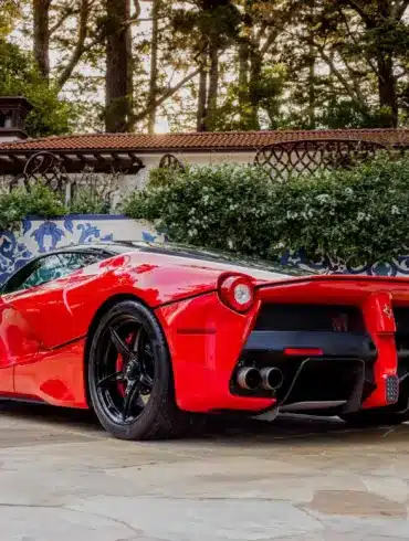 Ferrari LaFerrari 2015 in Rosso Corsa, geparkt in mediterranem Garten, Heckansicht.