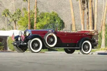 Lincoln Model L Sport Touring by Locke von 1929, kastanienrot mit schwarzen Kotflügeln, offen, mit weißen Wandreifen und zwei seitlichen Ersatzrädern.