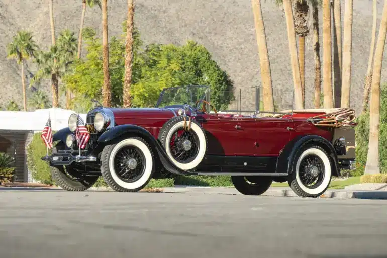 Lincoln Model L Sport Touring by Locke von 1929, kastanienrot mit schwarzen Kotflügeln, offen, mit weißen Wandreifen und zwei seitlichen Ersatzrädern.