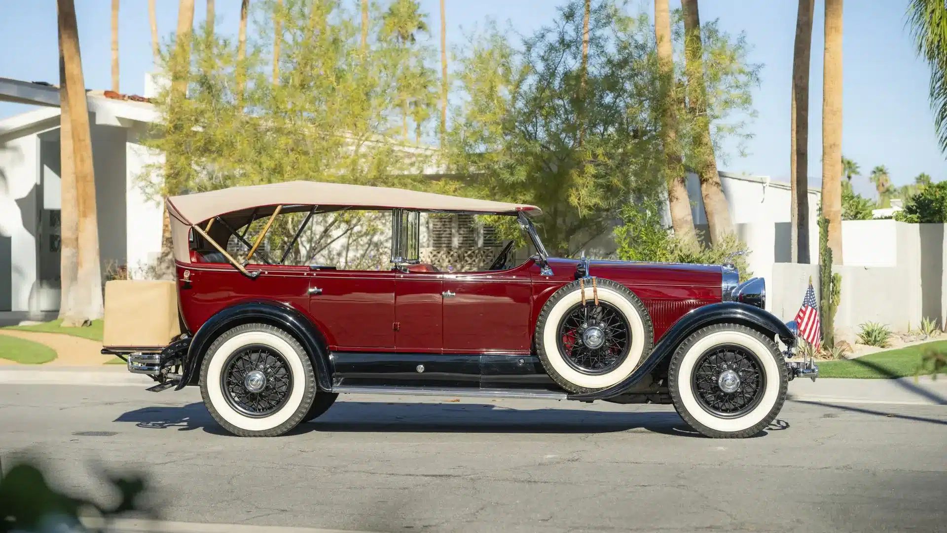 Lincoln Model L Sport Touring by Locke, Baujahr 1929, kastanienrotes Cabriolet mit beigem Verdeck und weißen Reifen, geparkt am Straßenrand.