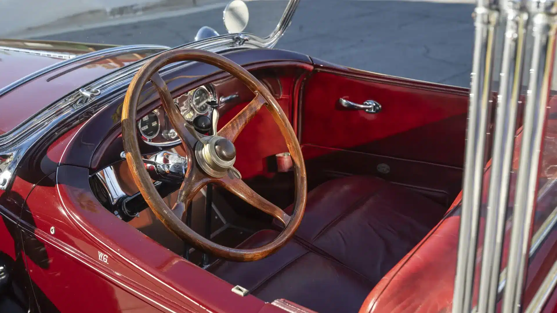 Detailaufnahme des Cockpits eines Lincoln Model L Sport Touring von 1929 mit Holzlenkrad und roten Ledersitzen.