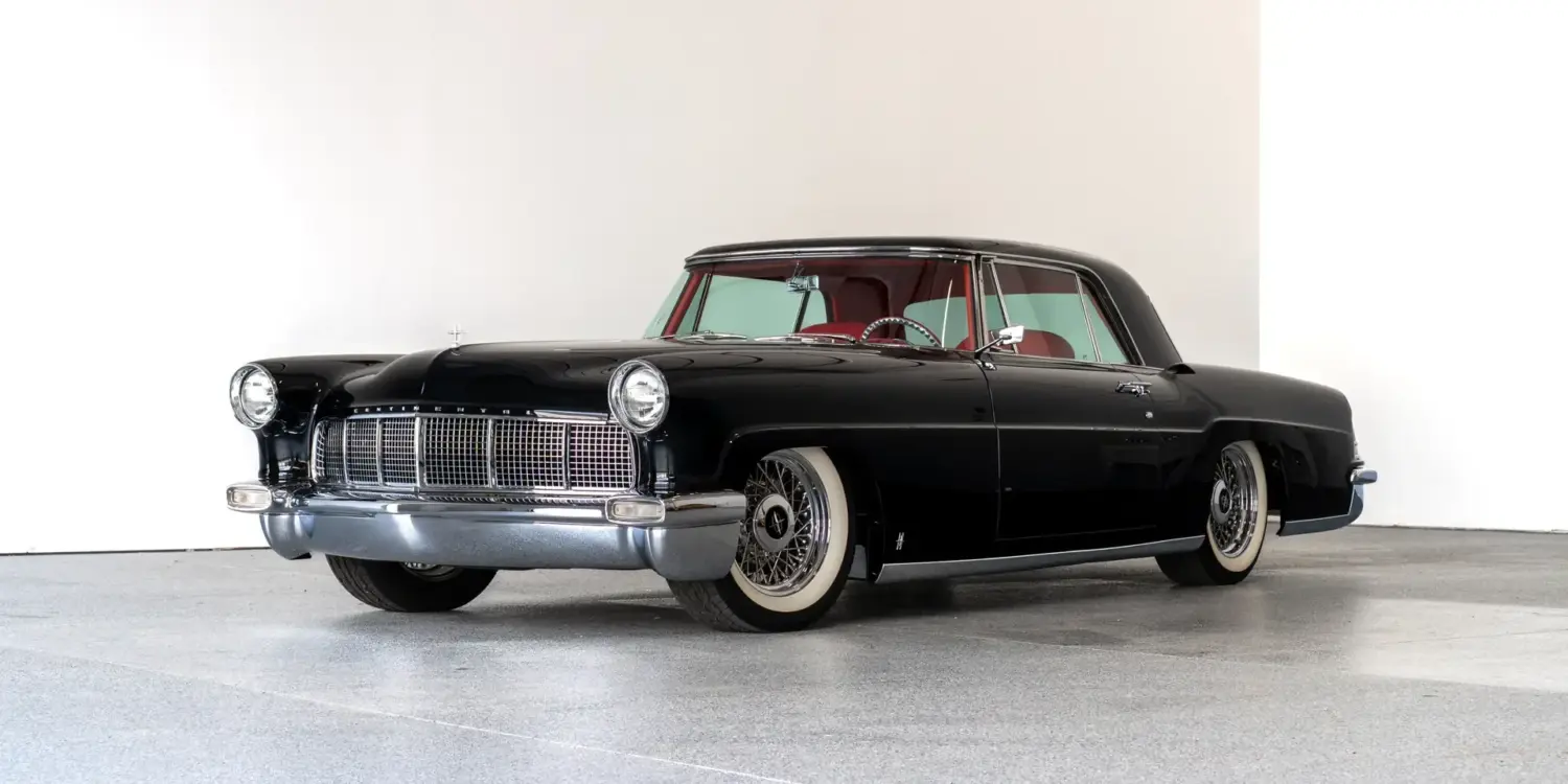Schwarzer Continental Mark II von 1956, modernisiert als Resto-Mod, mit rotem Interieur und Drahtspeichenrädern, seitlich fotografiert vor hellem Hintergrund.