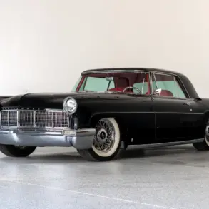 Schwarzer Continental Mark II von 1956, modernisiert als Resto-Mod, mit rotem Interieur und Drahtspeichenrädern, seitlich fotografiert vor hellem Hintergrund.