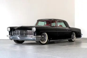 Schwarzer Continental Mark II von 1956, modernisiert als Resto-Mod, mit rotem Interieur und Drahtspeichenrädern, seitlich fotografiert vor hellem Hintergrund.