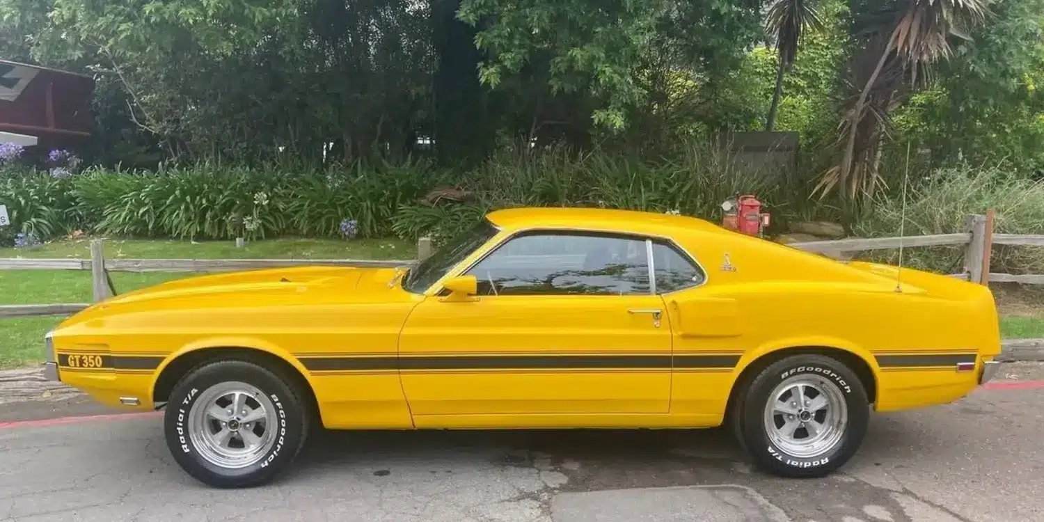 Gelber Shelby GT350 Baujahr 1969, amerikanisches Performance-Coupé, Seitenansicht auf offener Straße.