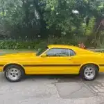 Gelber Shelby GT350 Baujahr 1969, amerikanisches Performance-Coupé, Seitenansicht auf offener Straße.