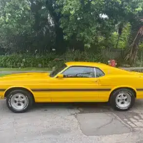 Gelber Shelby GT350 Baujahr 1969, amerikanisches Performance-Coupé, Seitenansicht auf offener Straße.
