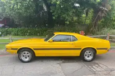 Gelber Shelby GT350 Baujahr 1969, amerikanisches Performance-Coupé, Seitenansicht auf offener Straße.