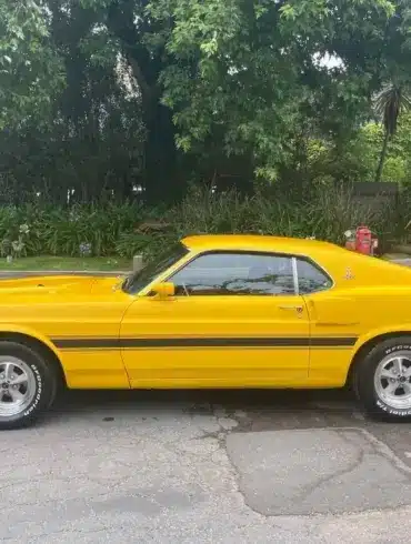 Gelber Shelby GT350 Baujahr 1969, amerikanisches Performance-Coupé, Seitenansicht auf offener Straße.
