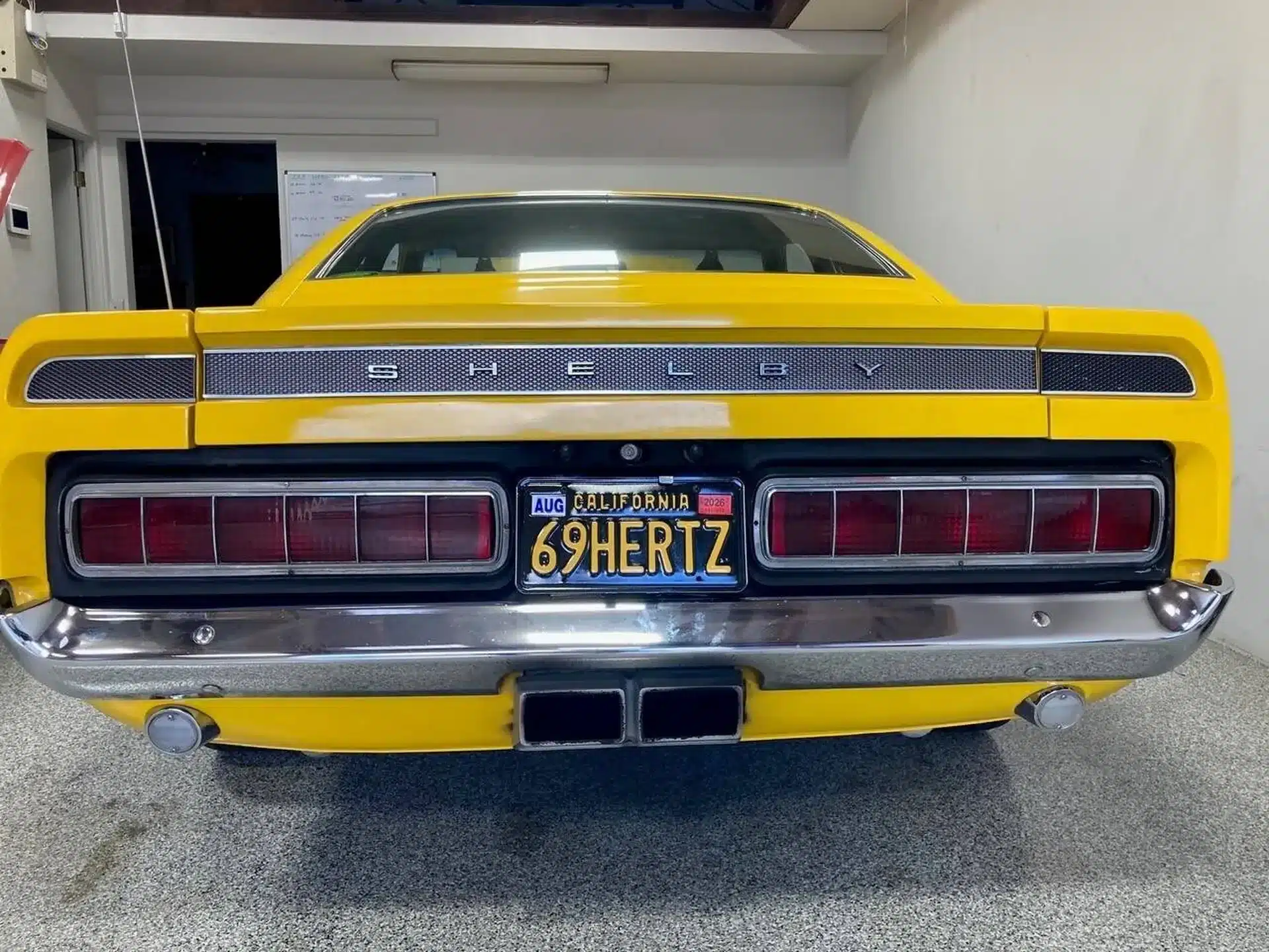 Heckansicht eines gelben Shelby-Modells von 1969 mit Kalifornien-Nummernschild, aufgenommen in einer Garage.
