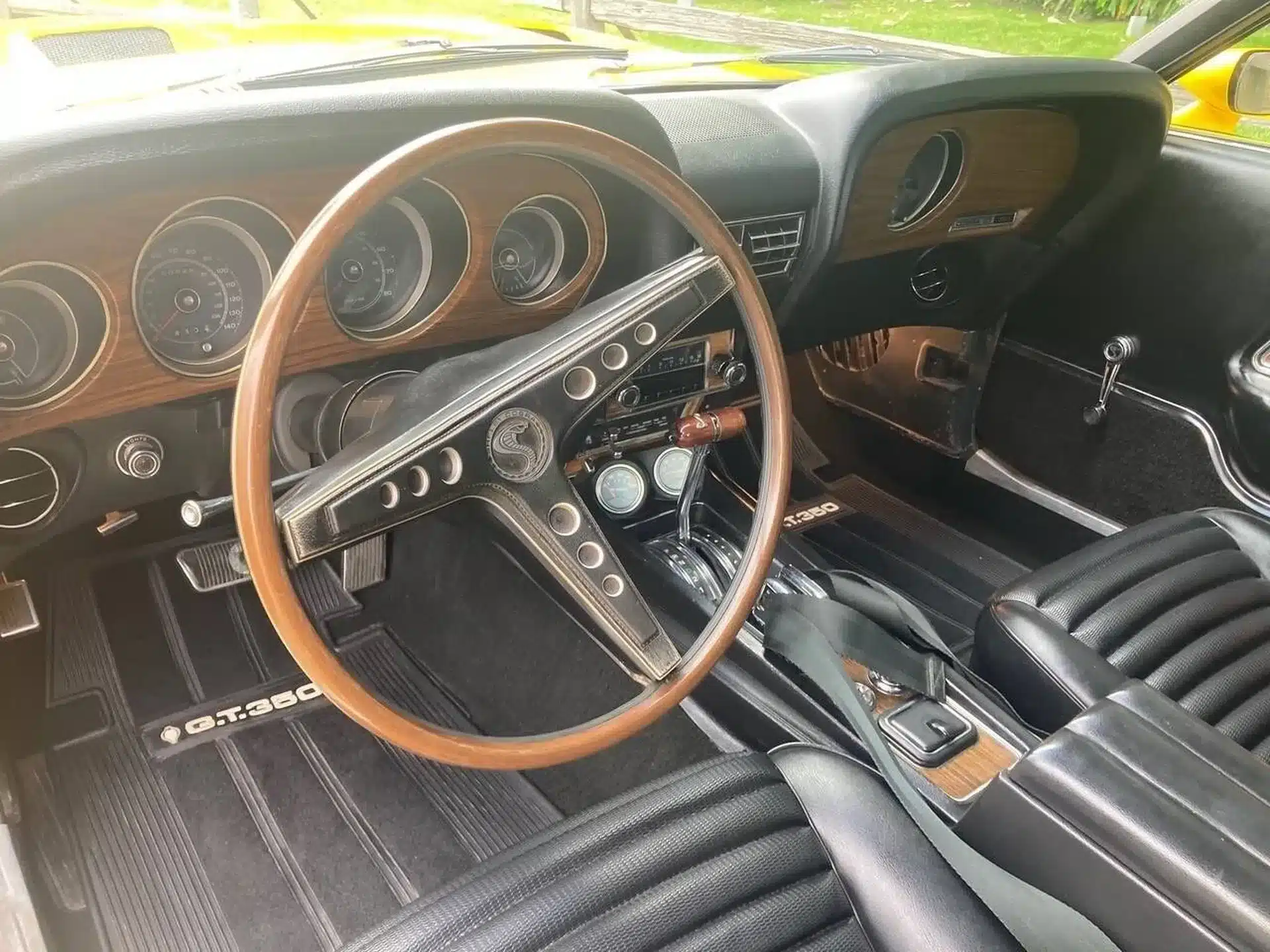 Lenkrad und Armaturenbrett eines Shelby GT350 aus dem Jahr 1969, Aufnahme des Innenraums mit typischem Holzdekor und Sportlenkrad.