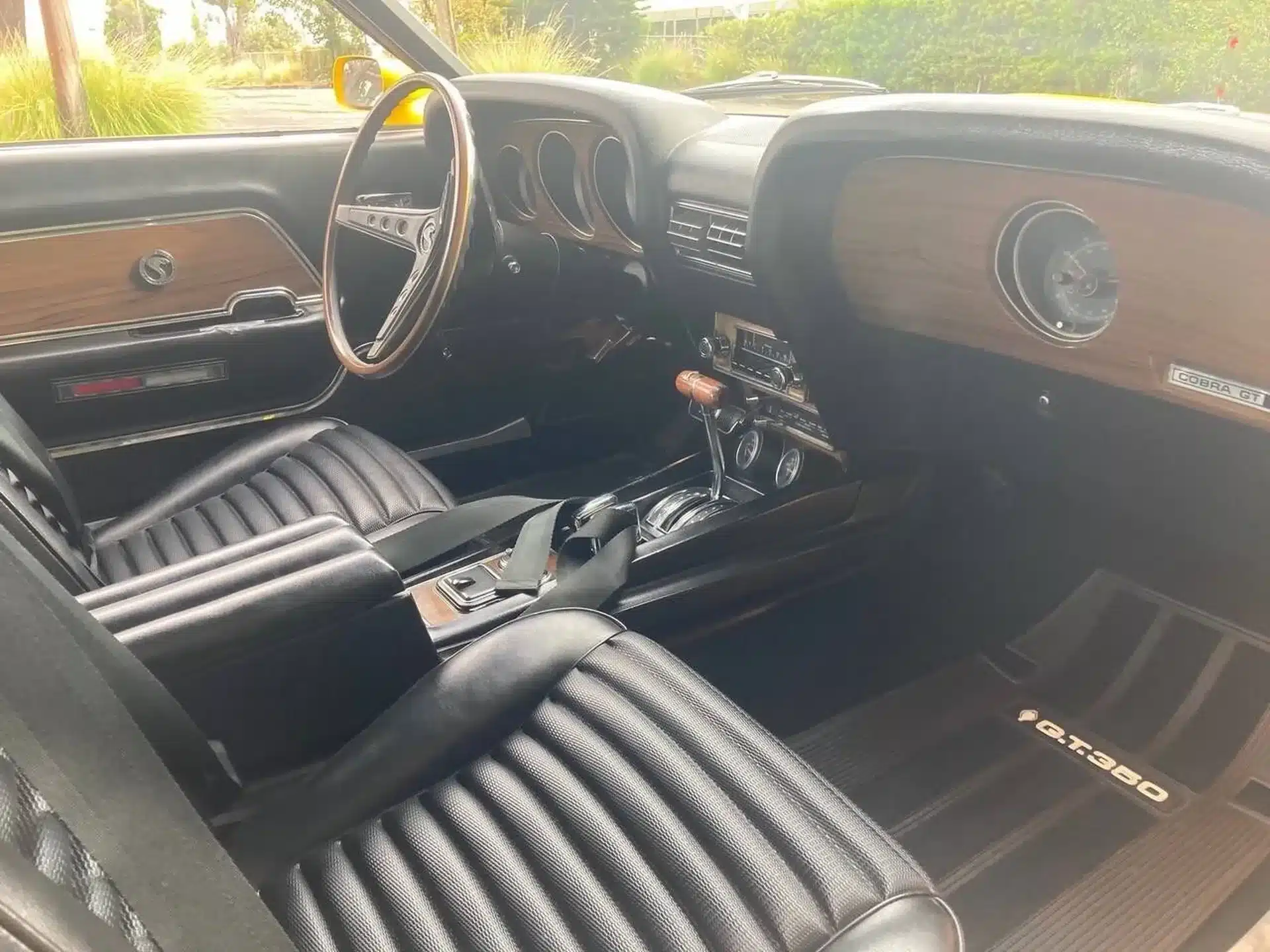 Innenraum eines Shelby GT350 aus dem Jahr 1969 mit schwarzem Leder, Holzarmaturenbrett und typischer GT350-Matte.