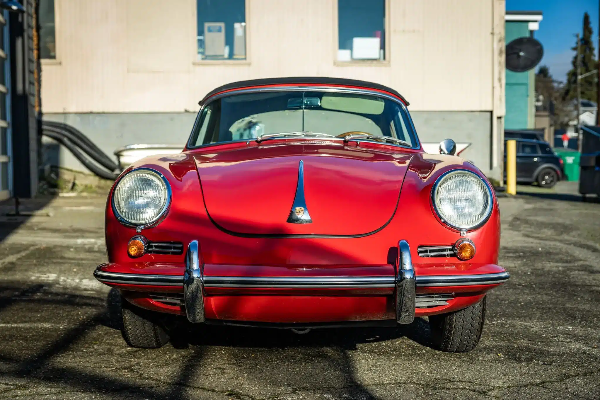 Frontansicht eines roten Porsche 356C Cabriolet von 1965 mit schwarzen Dach und Chromstoßfängern.