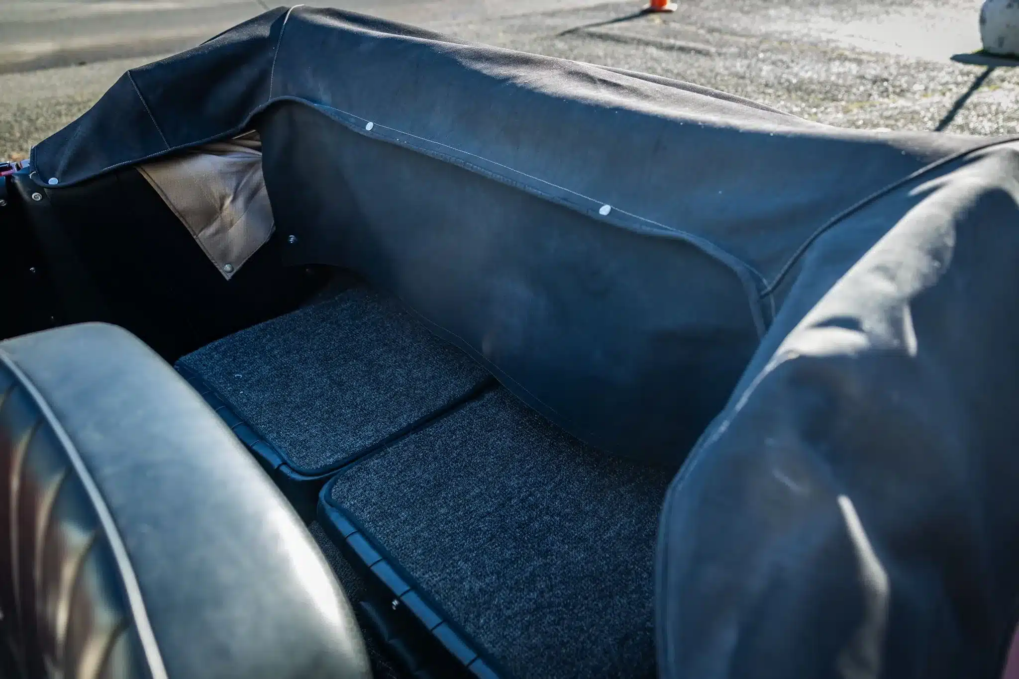 Rücksitzbank mit schwarzem Bezug und Teppich im Porsche 356C Cabriolet von 1965, Verdeck teilweise abgedeckt