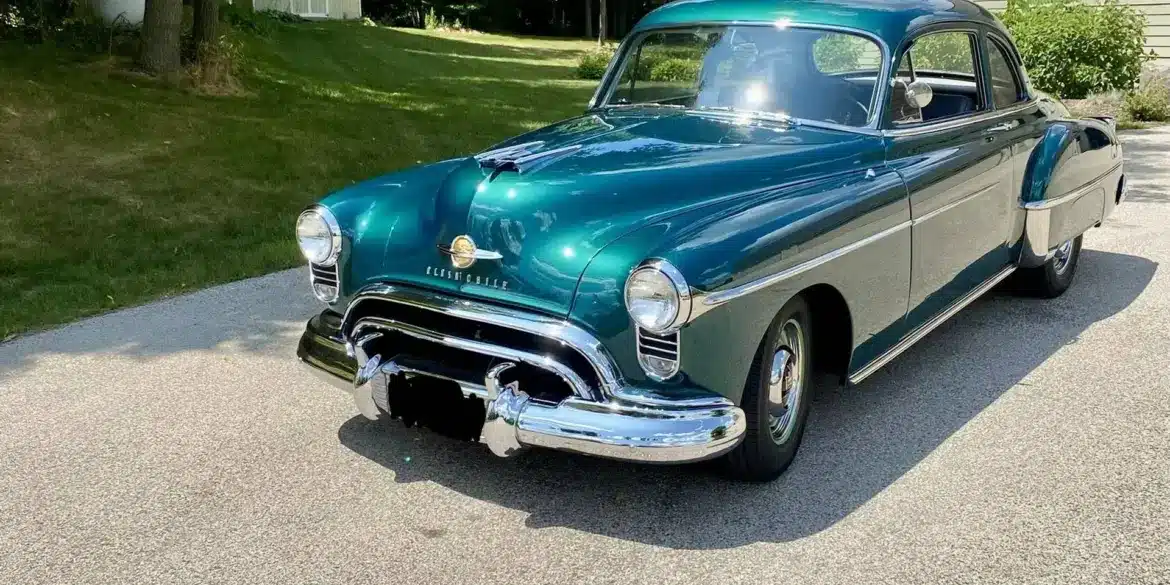 Grüner Oldsmobile 88 aus dem Jahr 1950 auf einer Einfahrt vor einem Wohnhaus, seitliche Frontansicht.