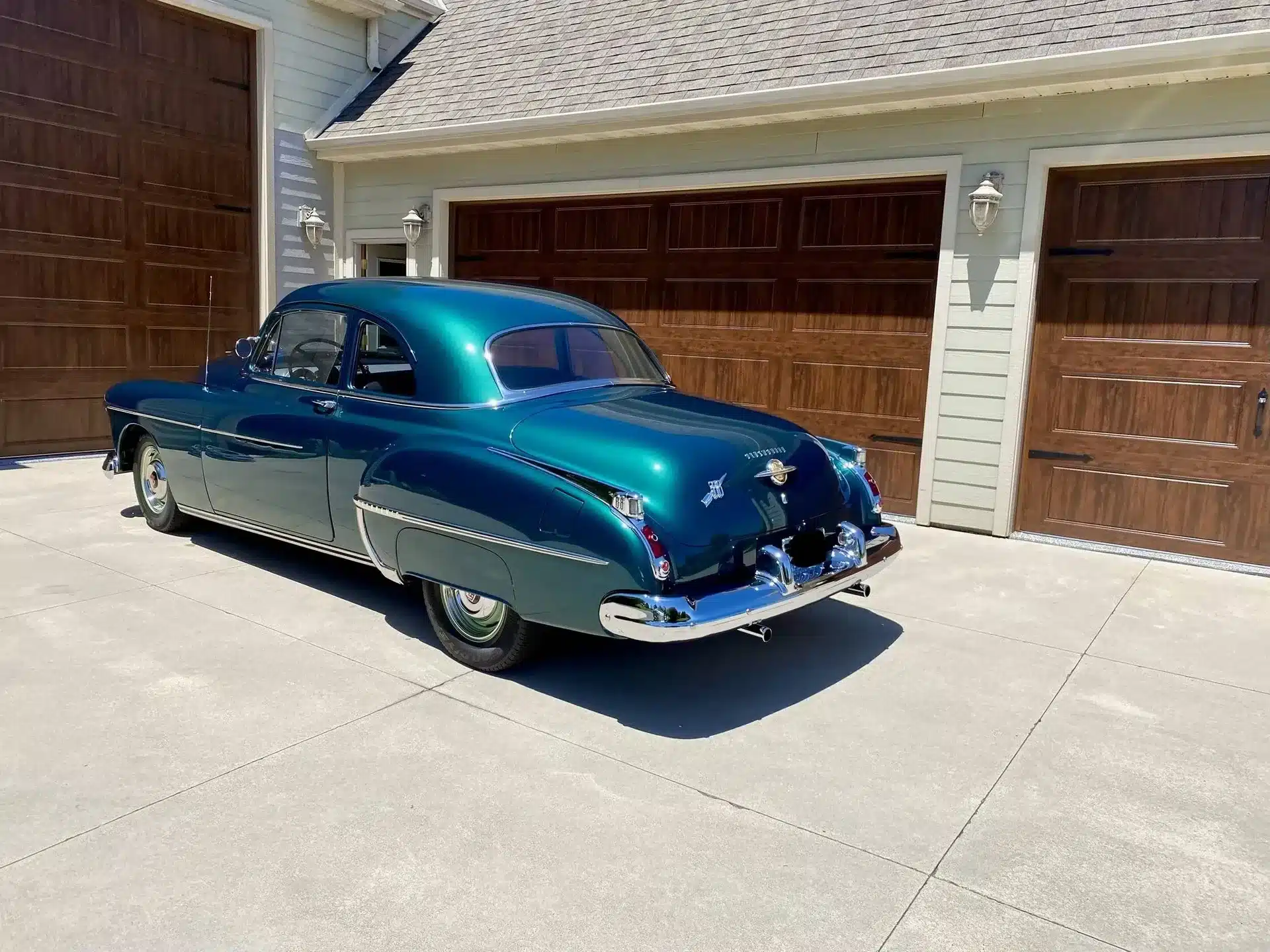 Oldsmobile 88 des Modelljahres 1950 in Dunkelgrün, fotografiert im Sonnenlicht vor einer Garage.