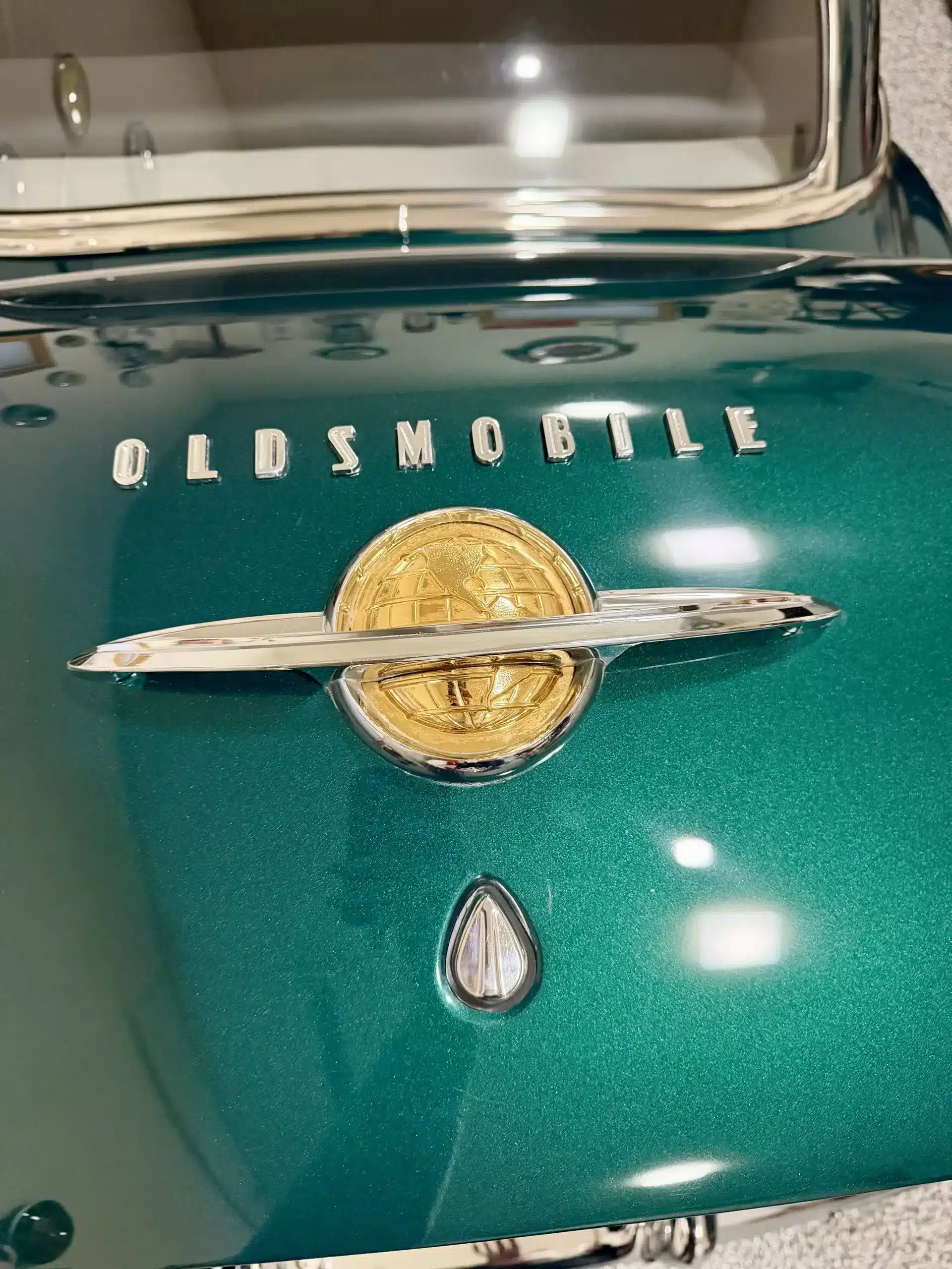 Emblem und Schriftzug eines Oldsmobile 88 von 1950 auf dem grünen Kofferraumdeckel.