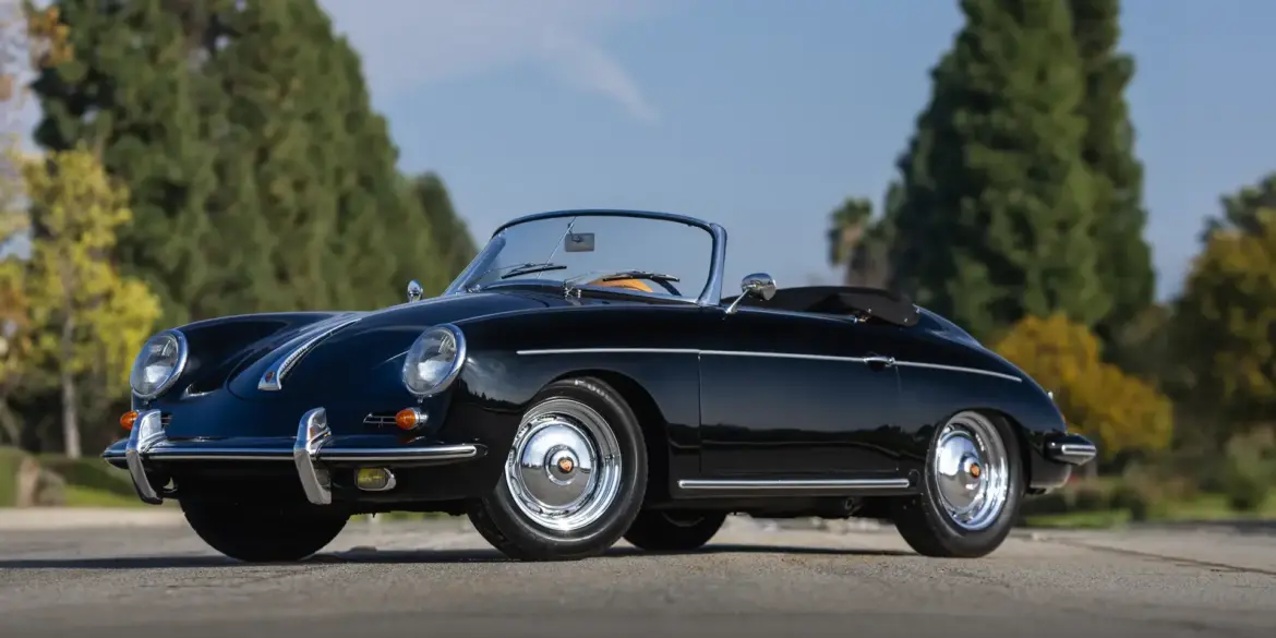 Schwarzer Porsche 356 B Super 90 Roadster von 1960, offen, frontal seitlich aufgenommen, vor unscharfem Grün im Hintergrund.