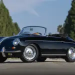 Schwarzer Porsche 356 B Super 90 Roadster von 1960, offen, frontal seitlich aufgenommen, vor unscharfem Grün im Hintergrund.