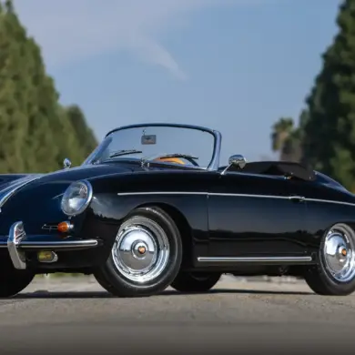 Schwarzer Porsche 356 B Super 90 Roadster von 1960, offen, frontal seitlich aufgenommen, vor unscharfem Grün im Hintergrund.